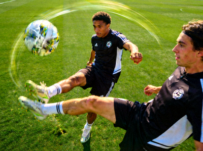 两名乐竞球员在进行快速一脚传球训练，足球在空中划出弧线